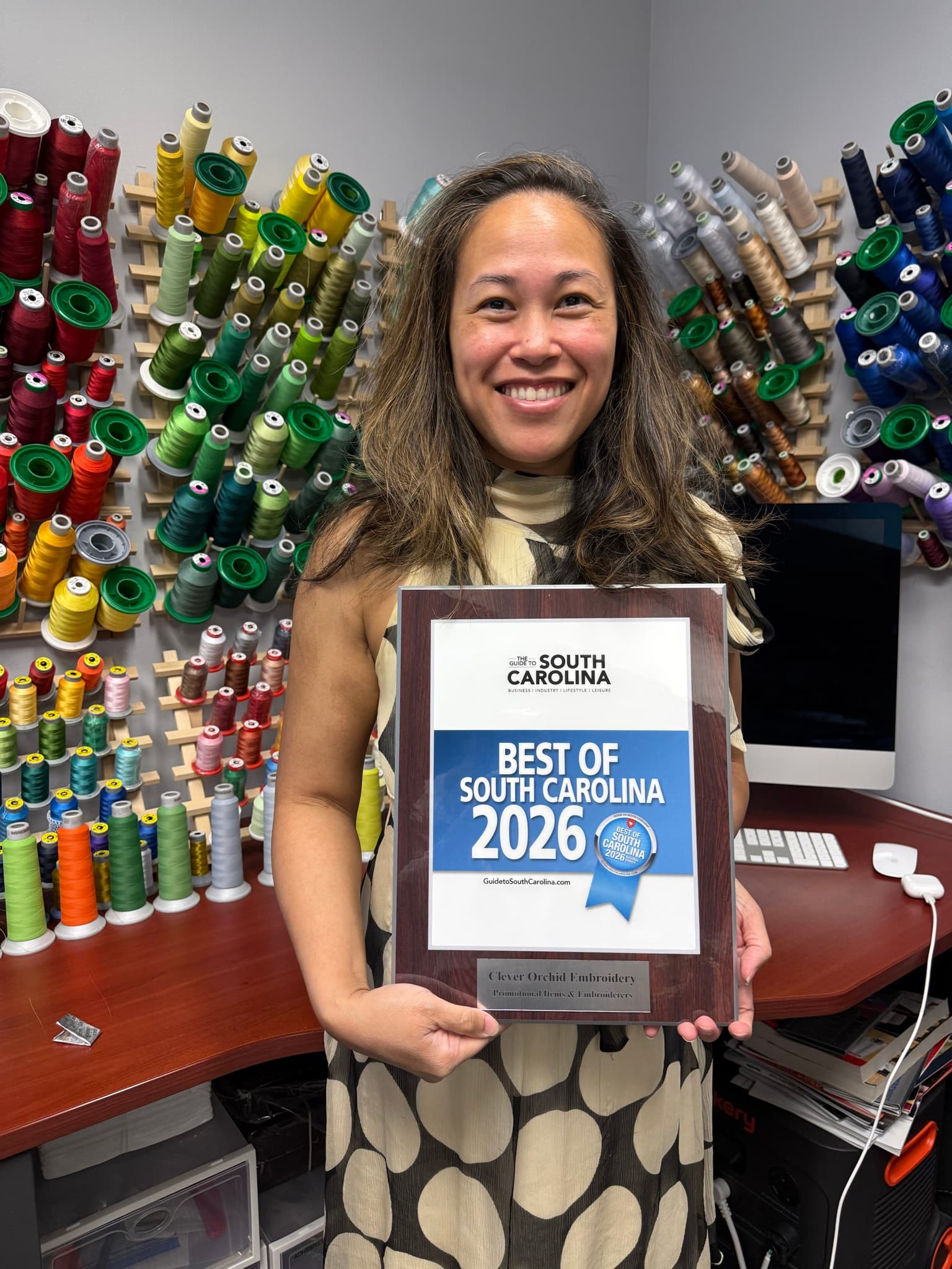Shirly holding the 2026 Best of South Carolina Regional Winner plaque for Promotional Items & Embroiderers at the Clever Orchid Embroidery studio in Columbia, SC